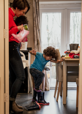 Mère qui encourage son fils à mettre ses bottes.