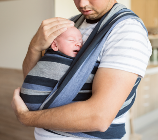 Père qui porte son nouveau-né dans une écharpe de portage