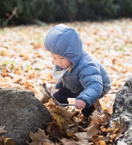 Un petit garçon s’amuse avec une branche et des feuilles mortes Un petit garçon s’amuse avec une branche et des feuilles mortes