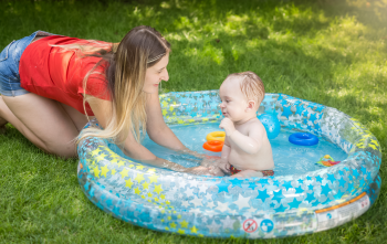 Bébé qui se baigne dans une piscine gonflable et sa mère le surveille Bébé qui se baigne dans une piscine gonflable et sa mère le surveille